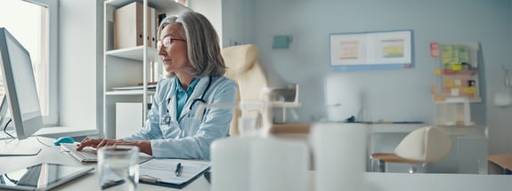 serious-mature-female-doctor-white-lab-coat-working-using-computer-while-sitting-her-office